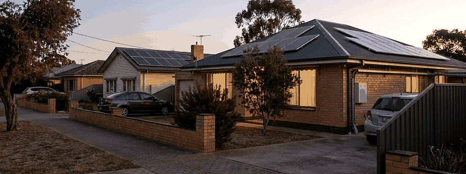 An Australian suburban street at evening with rooftop solar on several homes
